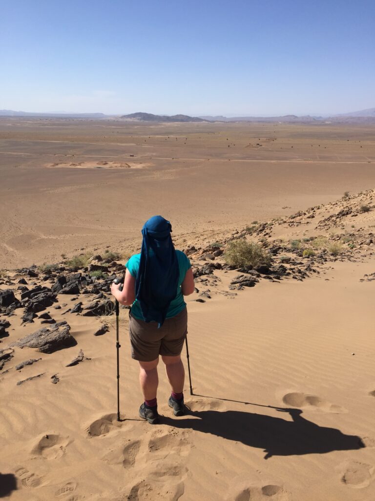Zoe Carroll standing in the Sahara desert wearing a headscarf. 