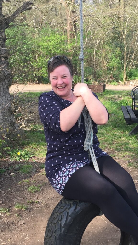 Zoe Carroll on a tyre swing, smiling. 